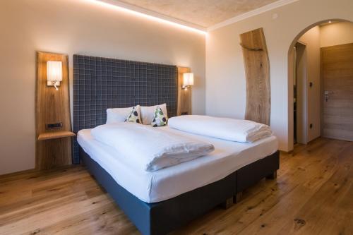 - une chambre dotée d'un grand lit avec des draps et des oreillers blancs dans l'établissement Hotel Garni Vigilhof, à Lana