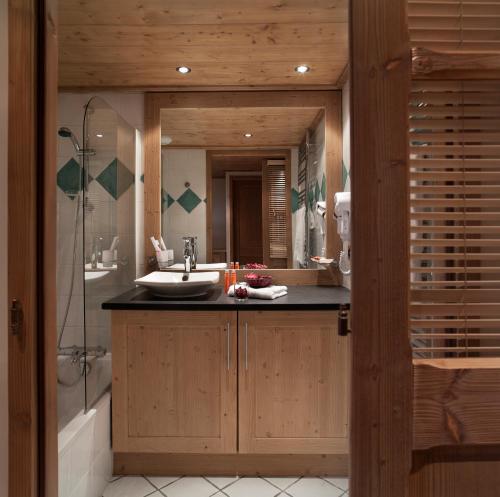 een badkamer met een wastafel, een douche en een spiegel bij CGH Résidences & Spas Les Chalets de Jouvence in Les Carroz d'Araches