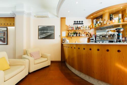 a bar with two white chairs and a counter at Hotel Cala Di Forno in Fonteblanda
