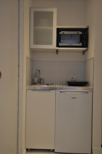 una pequeña cocina con armarios blancos y microondas en La Ginestra Amalfi Dreams, en Minori