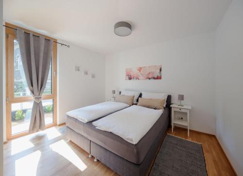 ein weißes Schlafzimmer mit einem Bett und einem Fenster in der Unterkunft Ferienwohnung Freiraum in Bernkastel-Kues