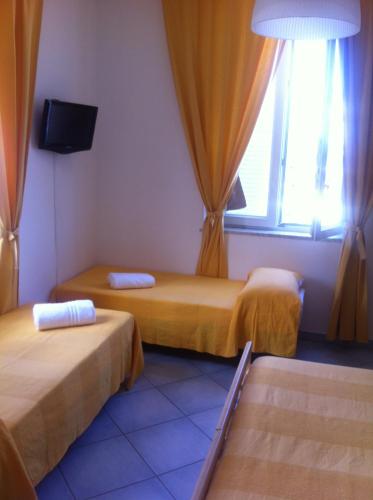 a room with two beds and a tv and a window at Excelsior Mare Suite in Ischia