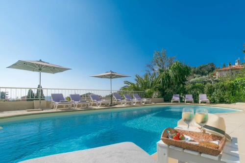 a swimming pool with chairs and umbrellas at Hôtel La Fiancée du Pirate in Villefranche-sur-Mer