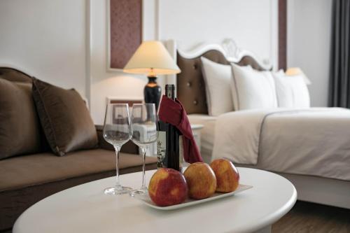 a room with a table with two wine glasses and a couch at Bonsella Hotel in Hanoi
