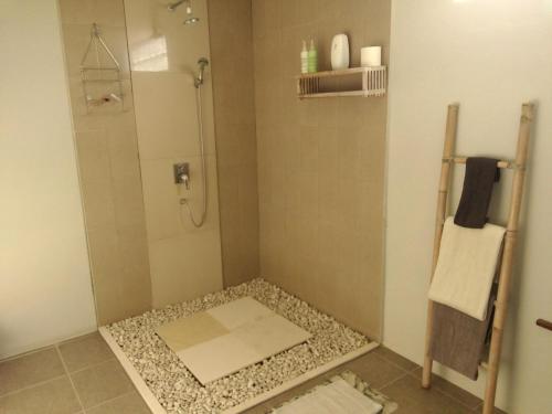 y baño con ducha y suelo de guijarros. en Aquaria Eco Resort en Candidasa