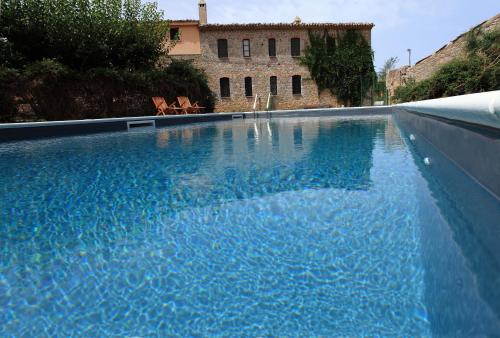 a swimming pool with blue water in front of a building at Fattoria Mongerrate in Isnello