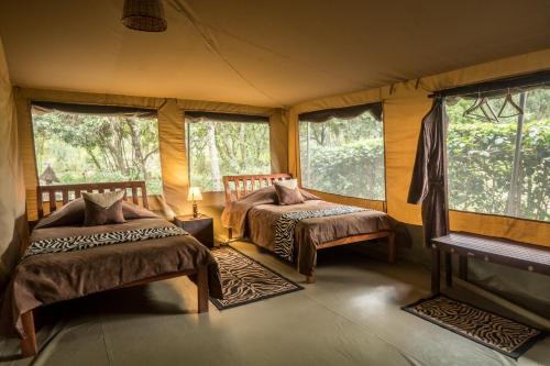 a bedroom with two beds in a room with windows at Rhino Watch Safarilodge in Mweiga