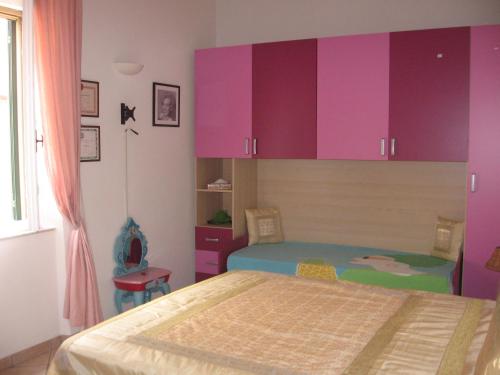 ポルトフェッラーイオにあるSansoneのピンクと紫のキャビネットとベッドが備わるベッドルーム1室