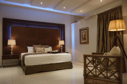 um quarto com uma cama grande, uma mesa e candeeiros em Hotel 2001 em Maputo