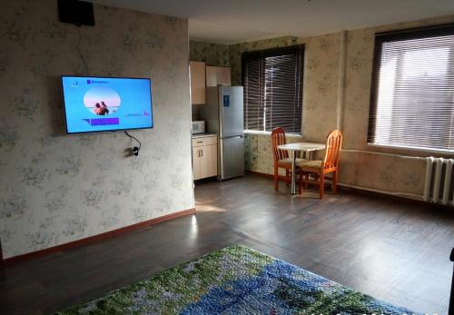 a kitchen with a table and a television on a wall at Zavenyagina 4 Apartment in Noril'sk