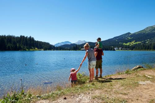 a family standing by a lake holding hands at Lai Lifestyle Hotel in Lenzerheide