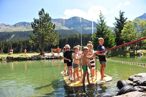 a group of children standing on a paddle board in the water at Lai Lifestyle Hotel in Lenzerheide