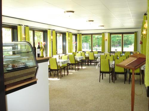 a dining room with green chairs and tables and windows at Mikkelborg Kro in Rødding