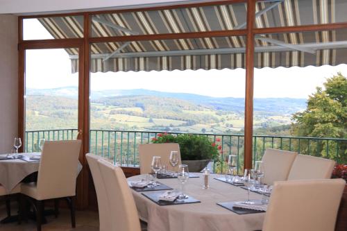 een eetkamer met een tafel en stoelen met uitzicht bij Logis Au Vieux Morvan "fait peau neuve" in Château-Chinon