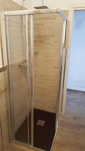 a shower with a glass door next to a wooden wall at Casa Mafalda in Chioggia