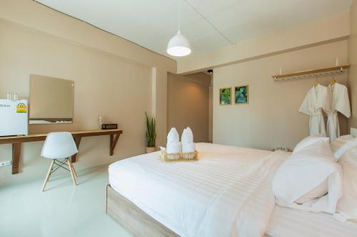 a bedroom with a large white bed and a desk at Habitat Hotel in Chiang Mai
