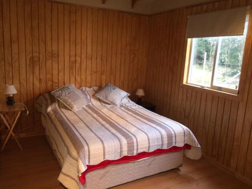 Cama en habitación de madera con ventana en Turismo Montaña Puerto Varas, en Puerto Varas