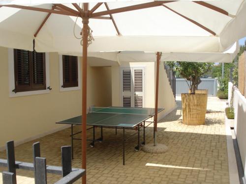 a ping pong table under an umbrella on a patio at Residence Casa Del Mar Sicilia in Marina di Modica