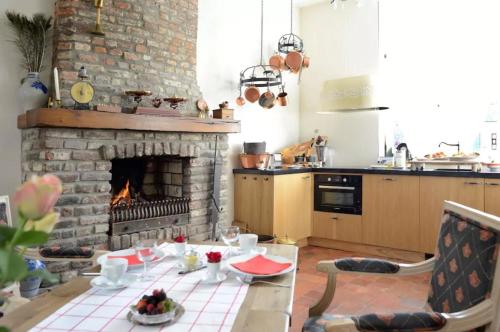 uma cozinha com uma lareira de tijolos e uma mesa e uma cozinha com uma mesa; em Artagnan em Maastricht