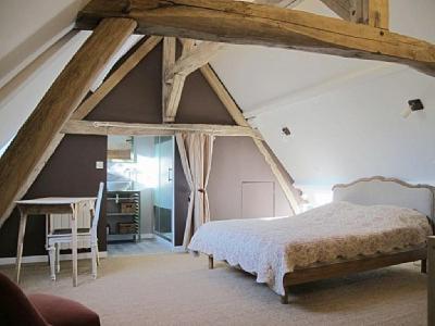 een slaapkamer met een bed en een bureau op zolder bij Le four à pain in Varennes