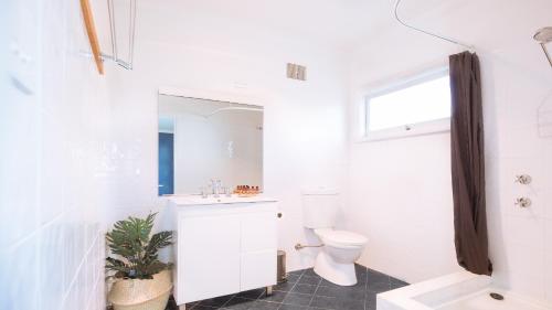 a white bathroom with a toilet and a sink at The River Retreat in Sussex inlet