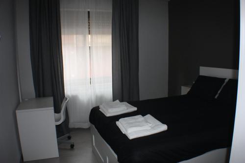 ヒホンにあるSagrado Corazonのベッドルーム1室(黒いベッド1台、タオル付)