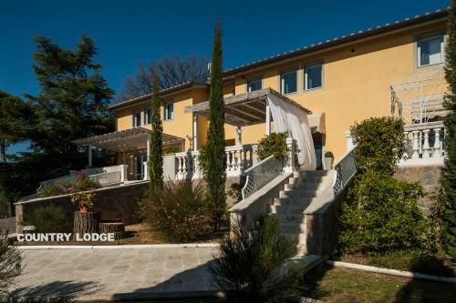 a large yellow building with stairs and trees at Country Lodge B&B in Siena