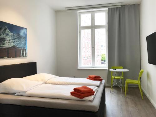 two beds in a room with a window and a table at Gästezimmer an der Elbphilharmonie contactless Check in in Hamburg