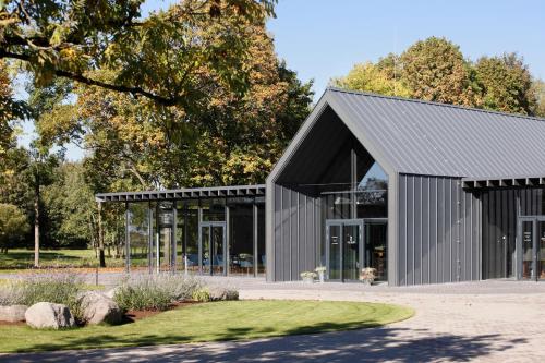 a large metal building with a black roof at Zoltners Hotel in Tērvete