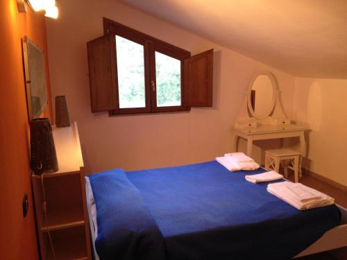 a bedroom with a blue bed and a mirror at Locanda La Corte in Serramezzana