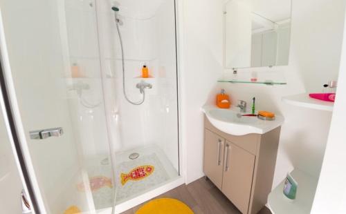 une salle de bain blanche avec une douche et un lavabo dans l'établissement Camping Les Charmettes-Mobile Home Vacances, aux Mathes