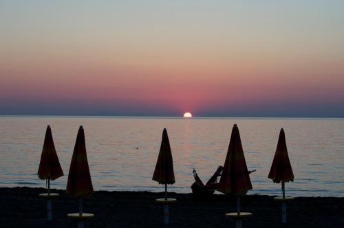 a group of umbrellas on the beach at sunset at Hotel Villa Smeraldo in Orbetello