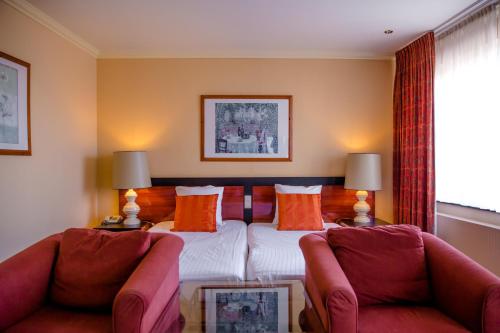 pokój hotelowy z łóżkiem i 2 krzesłami w obiekcie Hampshire Hotel – Voncken Valkenburg w mieście Valkenburg