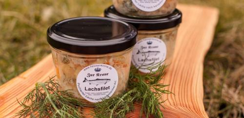 two jars of jam on a wooden tray with herbs at Hotel Zur Krone in Ronneburg