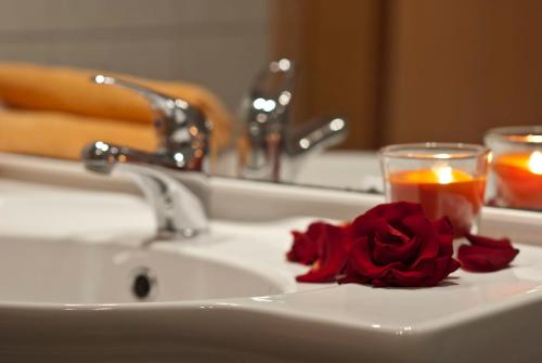 a bathroom sink with a rose and a candle at Ferienzimmer Am Brauhausgraben in Lübbenau