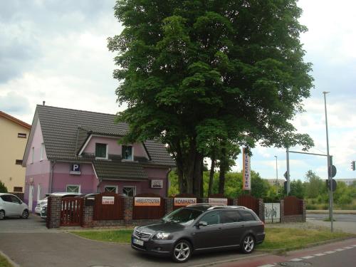 a black car parked in front of a pink house at Gästehaus Sol Tour in Ahrensfelde