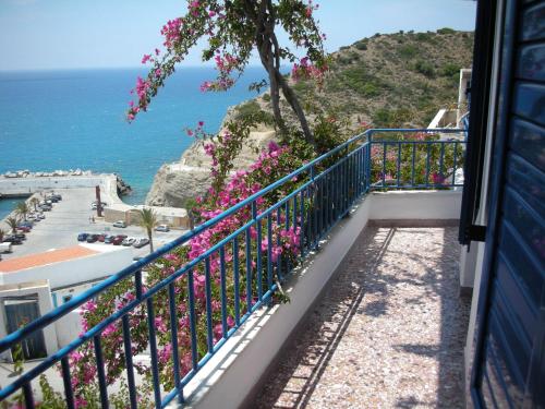 a balcony with flowers and the ocean in the background at Hotel Hariklia in Agia Galini