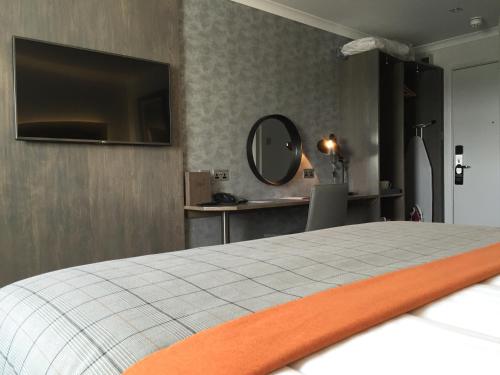 a bedroom with a bed with a tv on the wall at The Gailes Hotel & Spa in Irvine