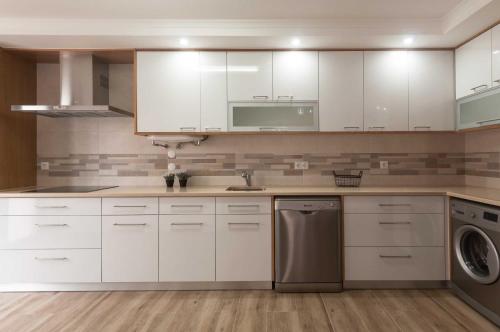a kitchen with white cabinets and a dishwasher at WestSide Beach House in Peniche de Cima