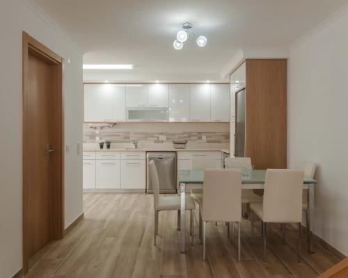 a kitchen with a dining room table and white cabinets at WestSide Beach House in Peniche