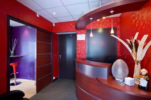 eine Lobby mit roten Wänden und einem Schreibtisch in einem Zimmer in der Unterkunft Hotel du 6 juin in Sainte-Mère-Église