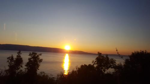 a sunset over a body of water with the sun setting at Apartments Stengl in Rab