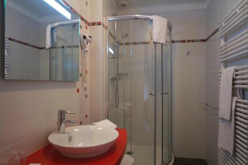 a bathroom with a sink and a glass shower at Hostellerie Saint Germain in Saint-Germain-lès-Arlay