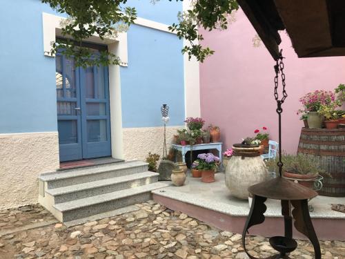 a pink house with a blue door and some potted plants at Vesta in Sorgono