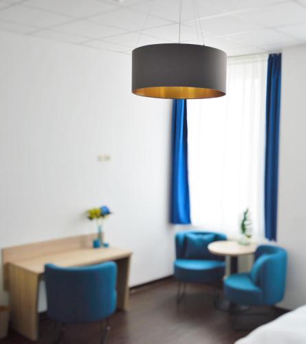 a hotel room with blue chairs and a table and a lamp at Pallas Hotel in Darmstadt