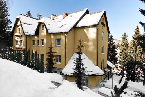 a large yellow house with snow on the roof at Hotel Vivaldi in Karpacz