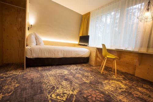 a hotel room with a bed and a yellow chair at Landgoed ISVW in Leusden