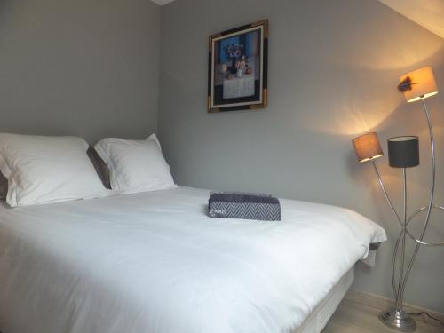 Un dormitorio con una cama blanca con una bolsa negra. en L'Eugenie en Pierrefonds
