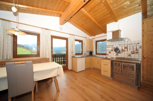 cocina con suelo y ventanas de madera y mesa en Oberpiskoihof, en Funes