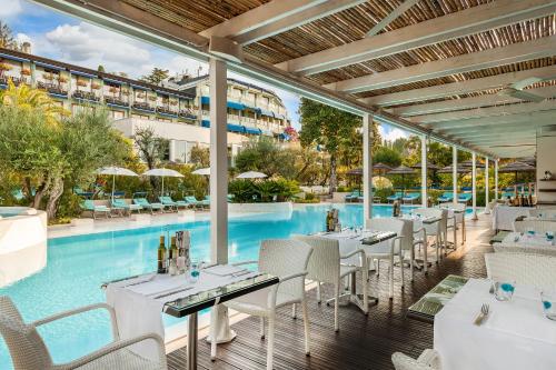 un ristorante con piscina con tavoli e sedie di Olivi Hotel & Natural Spa a Sirmione